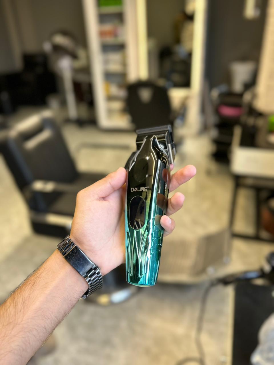 Hand holding a teal and black hair clipper in a salon setting